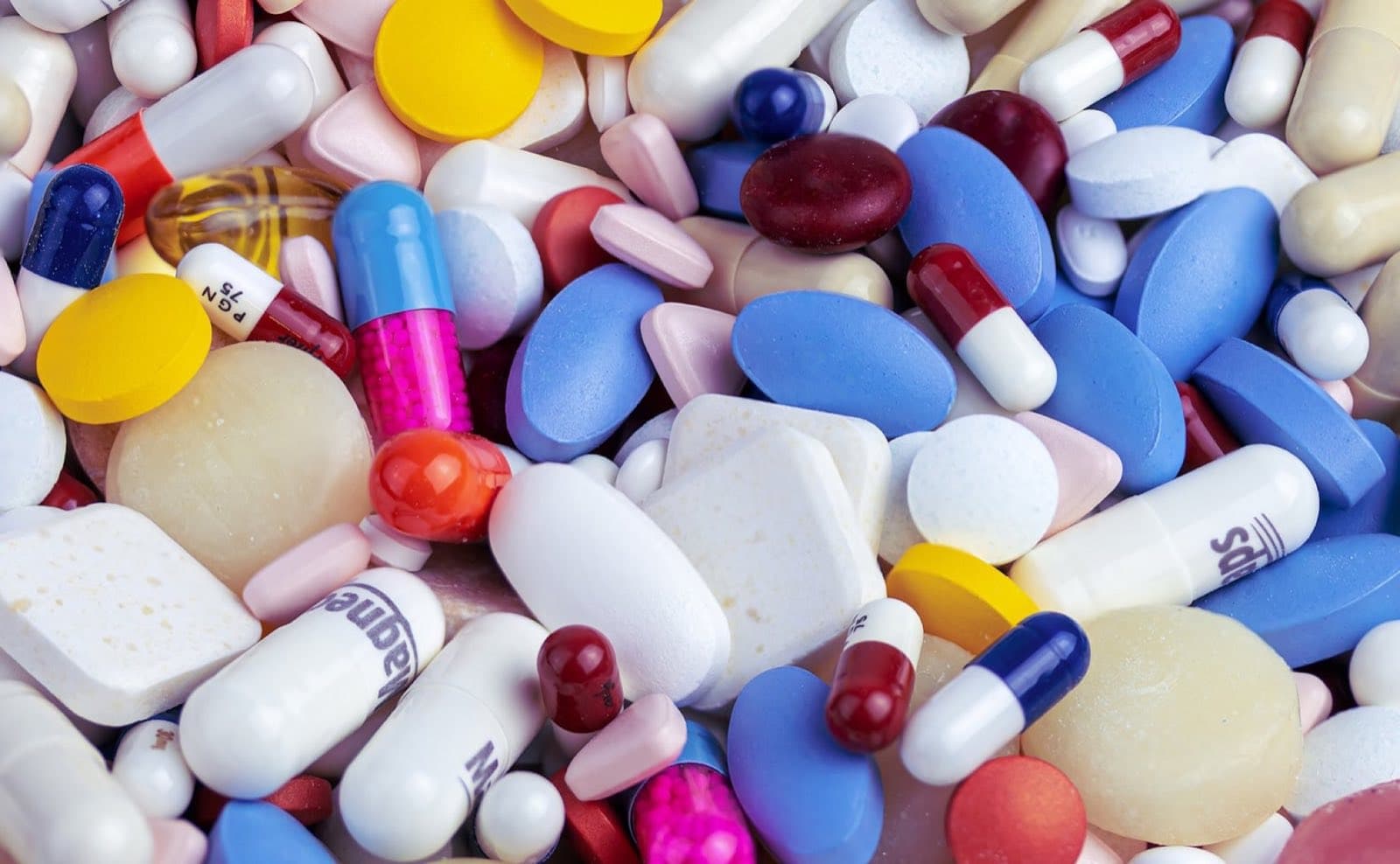 Pills and capsules of many colours and shapes, close up.