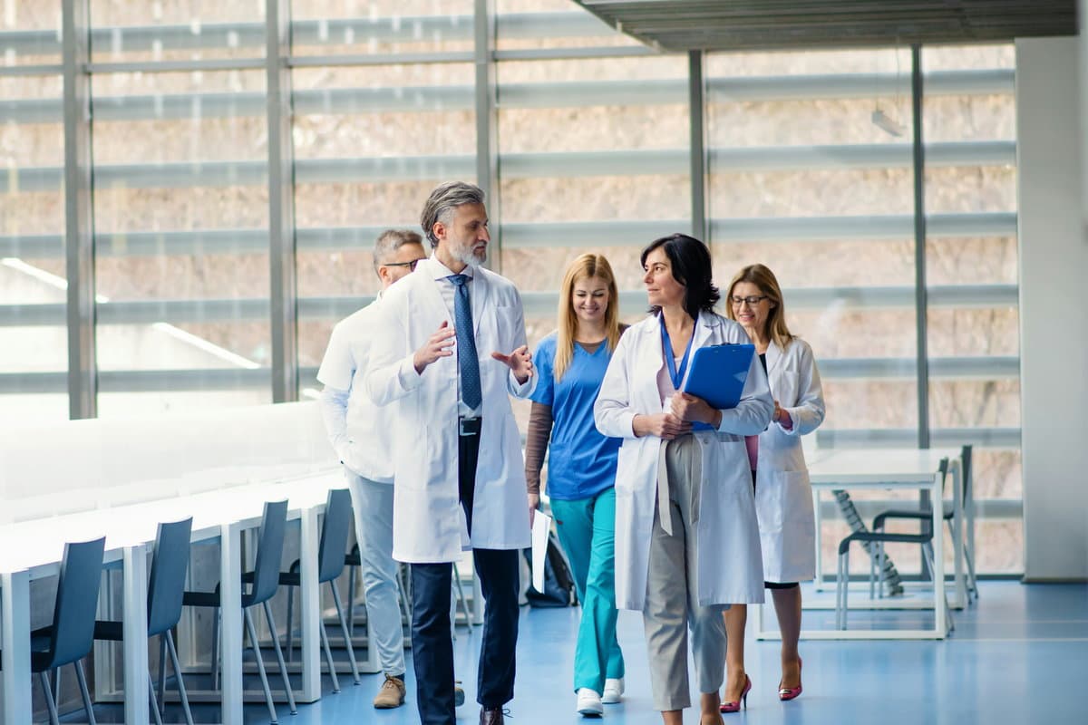 Three clinicians conferring in a hospital corridor.